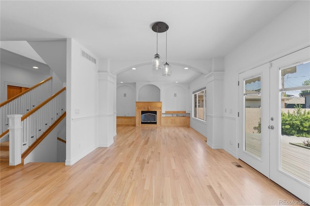 1172 S Steele St, Denver, CO 80210 - unfurnished living room featuring light wood-type flooring, arched walkways, recessed lighting, a glass covered fireplace, and stairway