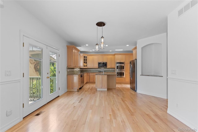 1172 S Steele St, Denver, CO 80210 - kitchen with stainless steel appliances, light wood finished floors, a kitchen island with sink, decorative backsplash, and glass insert cabinets
