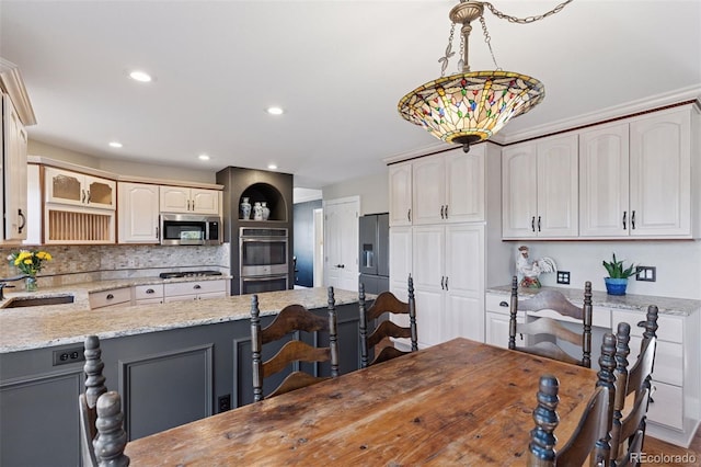 kitchen featuring light stone countertops, a sink, decorative backsplash, stainless steel appliances, and a kitchen bar