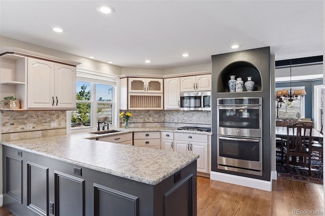 kitchen featuring a sink, appliances with stainless steel finishes, a peninsula, and open shelves