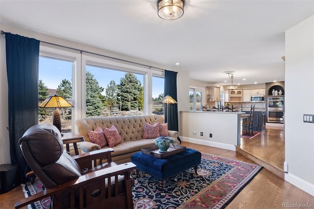 living area with a notable chandelier, recessed lighting, baseboards, and light wood-style floors