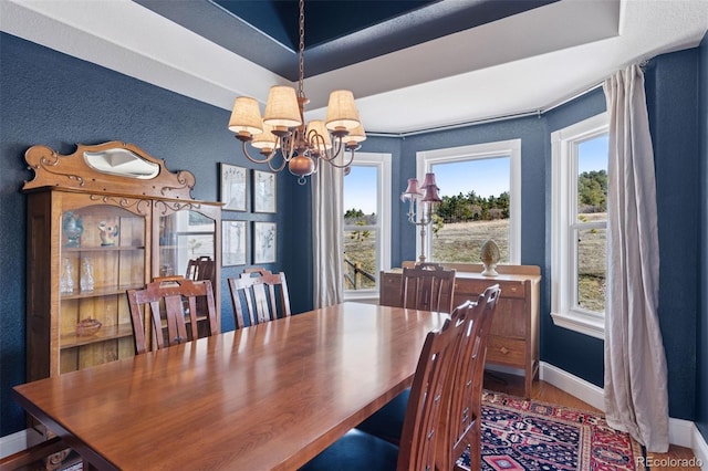 dining area featuring a wealth of natural light, a notable chandelier, baseboards, and wood finished floors