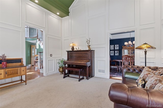 sitting room with light carpet, a decorative wall, and a high ceiling