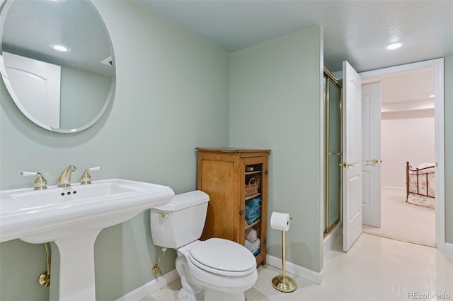 bathroom with baseboards, toilet, recessed lighting, a shower with shower door, and a sink