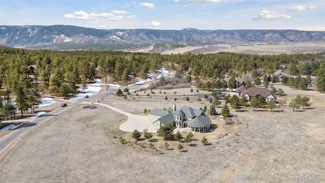 drone / aerial view featuring a wooded view and a mountain view