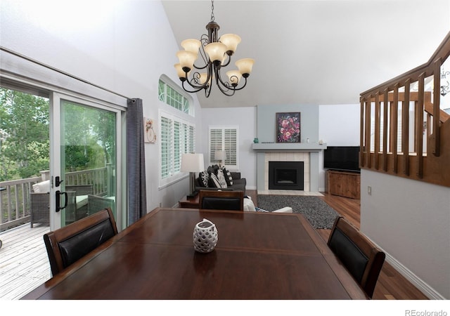 9864 Carmel Ct, Lone Tree, CO 80124 - dining space featuring a chandelier, wood finished floors, lofted ceiling, and a tile fireplace