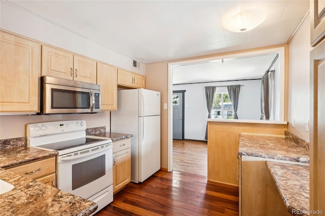 kitchen with white appliances, dark stone countertops, light brown cabinets, and dark wood-type flooring