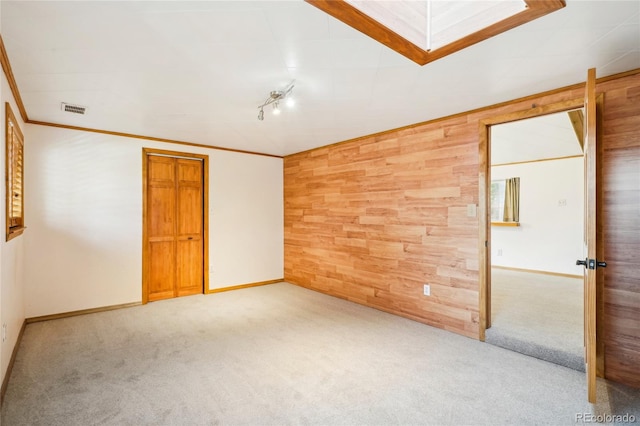 unfurnished room with ornamental molding, wood walls, and carpet flooring