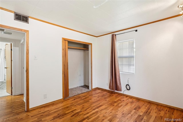 unfurnished bedroom featuring crown molding, a closet, and hardwood / wood-style flooring