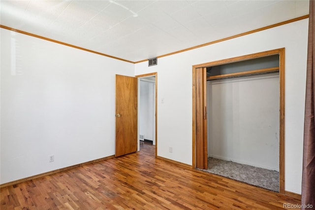 unfurnished bedroom with ornamental molding, a closet, and hardwood / wood-style floors