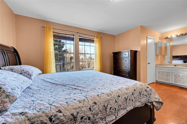 bedroom with connected bathroom and light wood-type flooring