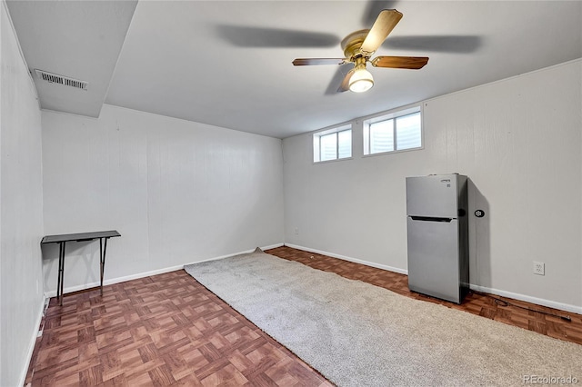 basement with ceiling fan, stainless steel fridge, and parquet floors