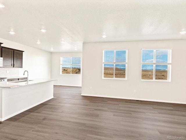 kitchen featuring dark hardwood / wood-style floors, sink, light stone counters, and dark brown cabinets