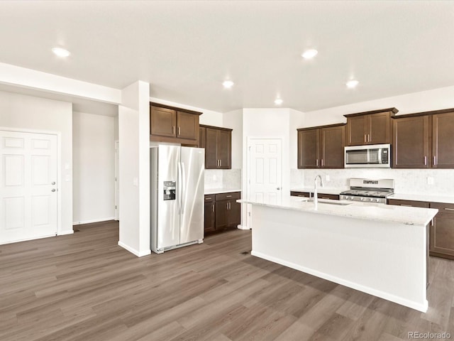 kitchen with tasteful backsplash, dark hardwood / wood-style floors, sink, a kitchen island with sink, and appliances with stainless steel finishes