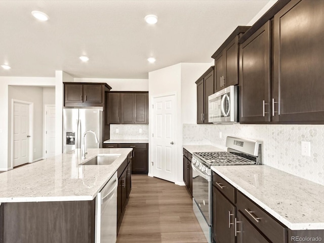 kitchen featuring sink, wood-type flooring, appliances with stainless steel finishes, and a center island with sink