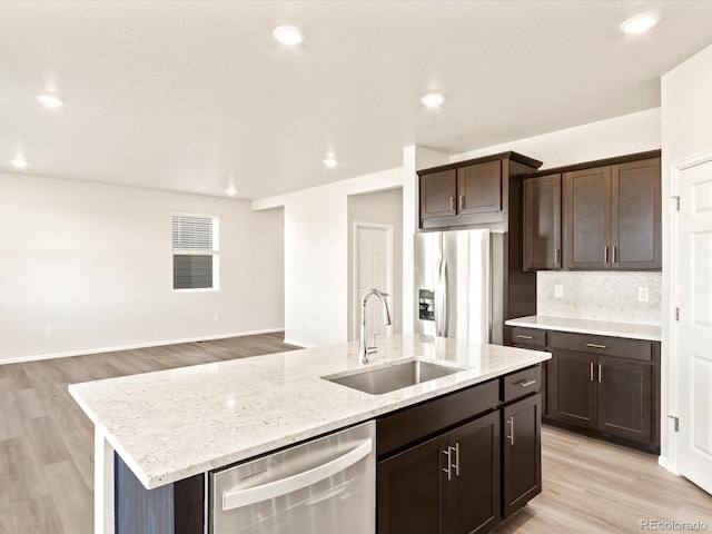 kitchen with light hardwood / wood-style floors, sink, stainless steel appliances, and a kitchen island with sink