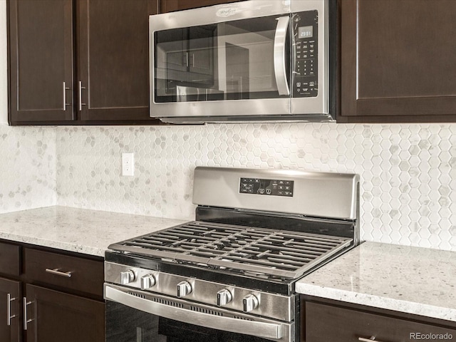 kitchen featuring stainless steel appliances, backsplash, dark brown cabinetry, and light stone countertops