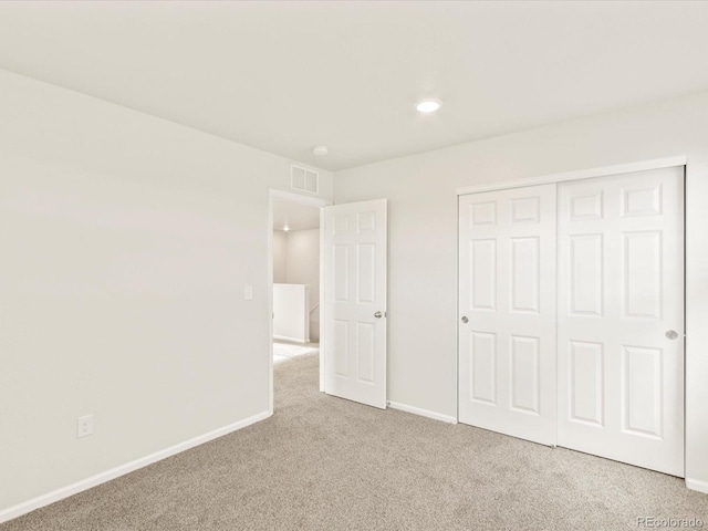 unfurnished bedroom featuring light colored carpet and a closet