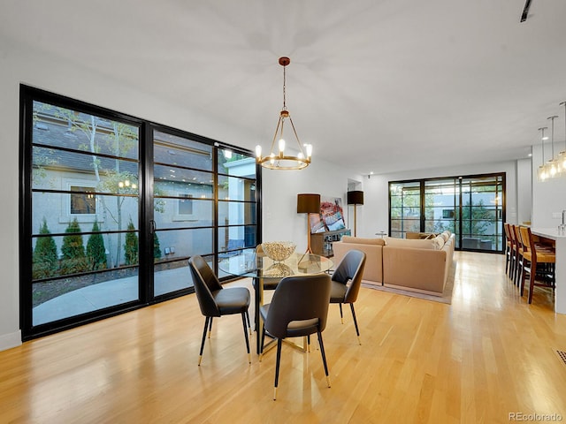 dining room with light wood-type flooring and an inviting chandelier