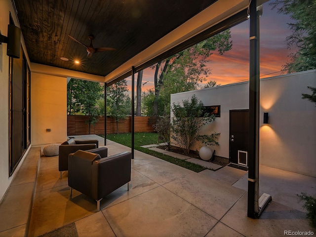 patio terrace at dusk featuring ceiling fan and an outdoor living space