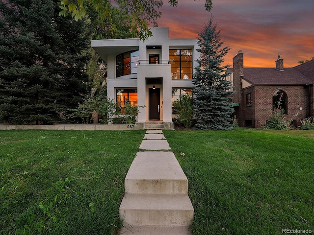 view of front of home with a lawn and a balcony