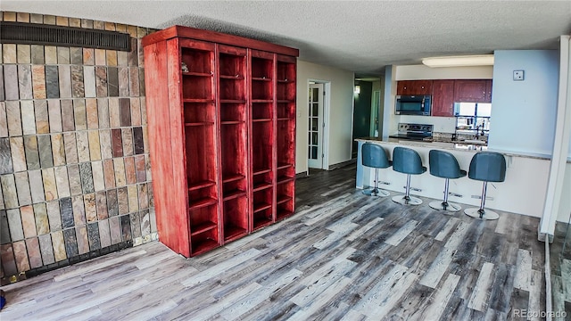 kitchen featuring hardwood / wood-style floors, a textured ceiling, kitchen peninsula, and stainless steel appliances