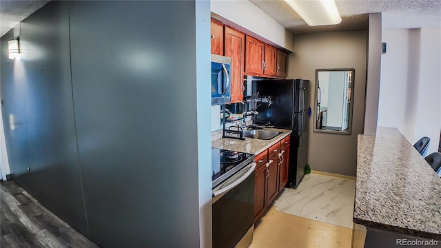 kitchen featuring a textured ceiling, hanging light fixtures, stainless steel appliances, and light wood-type flooring