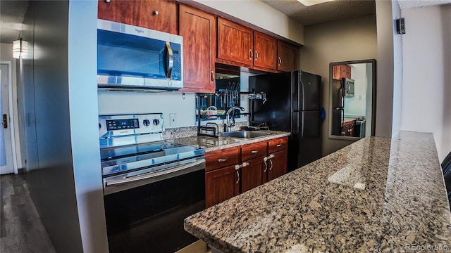 kitchen with a textured ceiling, dark hardwood / wood-style floors, appliances with stainless steel finishes, sink, and light stone counters