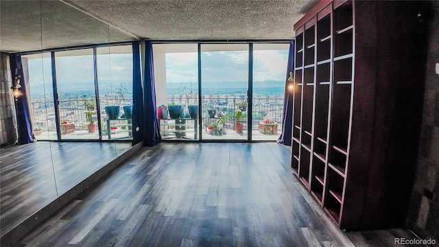 unfurnished room featuring a wall of windows, a wealth of natural light, dark hardwood / wood-style floors, and a textured ceiling