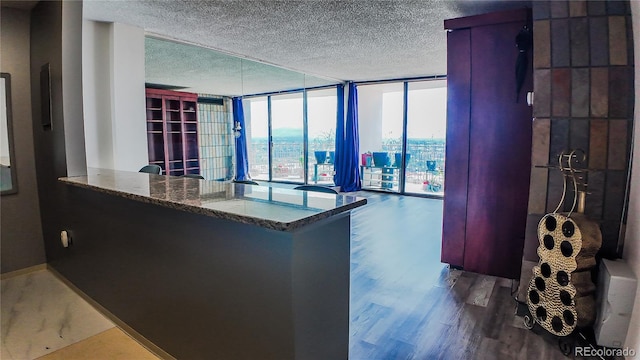 kitchen featuring a textured ceiling, hardwood / wood-style flooring, kitchen peninsula, and a wall of windows