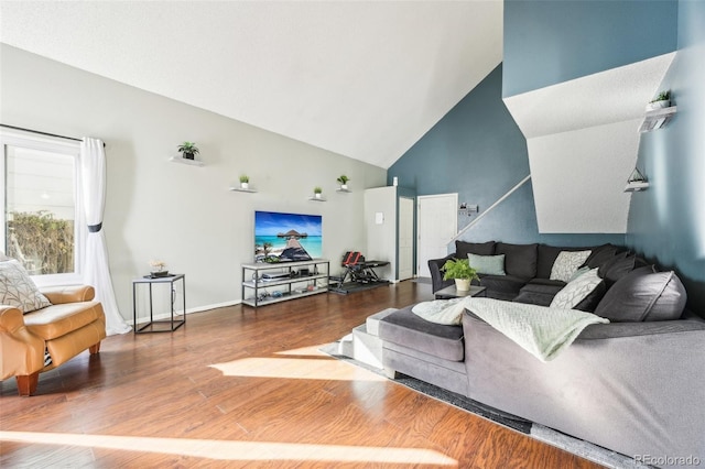 living room featuring high vaulted ceiling, baseboards, and wood finished floors