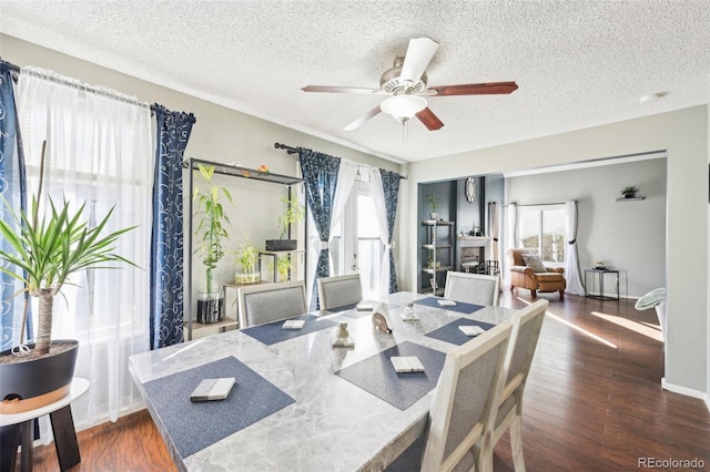 dining room with baseboards, a textured ceiling, a ceiling fan, and wood finished floors