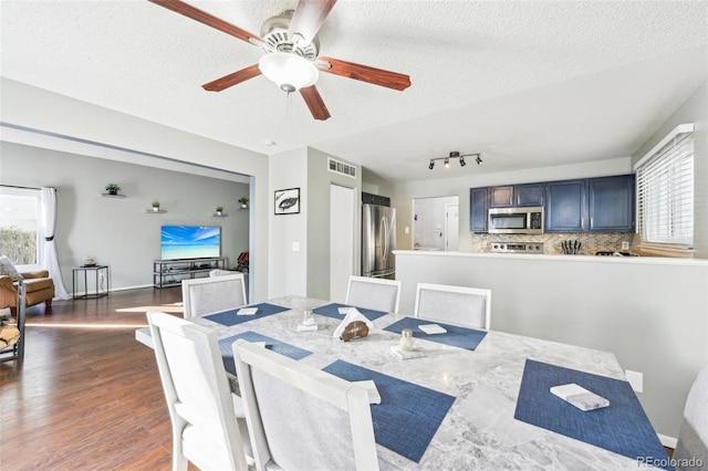 dining space featuring dark wood-style flooring, visible vents, a textured ceiling, and baseboards