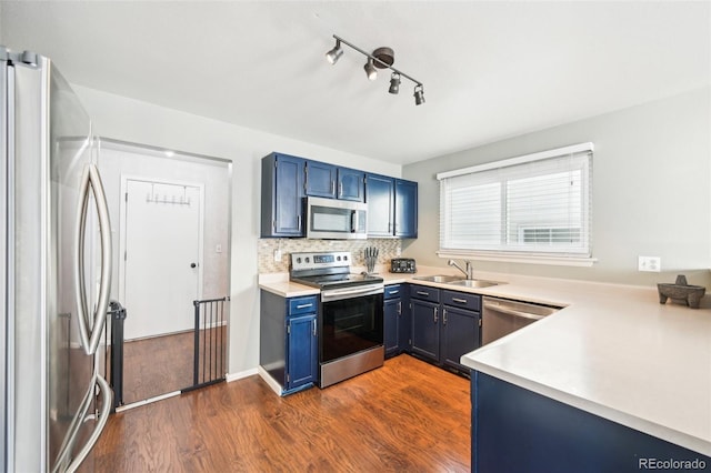 kitchen featuring dark wood-style flooring, light countertops, appliances with stainless steel finishes, a sink, and blue cabinets