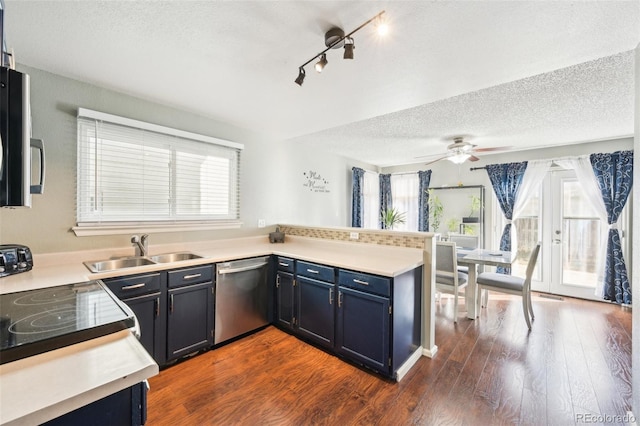 kitchen with dark wood finished floors, blue cabinetry, appliances with stainless steel finishes, a sink, and a peninsula