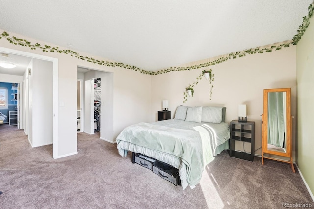 bedroom featuring a closet, carpet flooring, a walk in closet, and baseboards