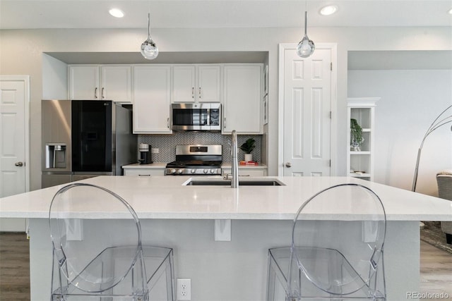 kitchen featuring appliances with stainless steel finishes, white cabinetry, wood finished floors, decorative light fixtures, and recessed lighting