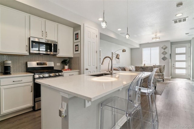 kitchen with stainless steel appliances, open floor plan, a sink, dark wood-style floors, and a textured ceiling