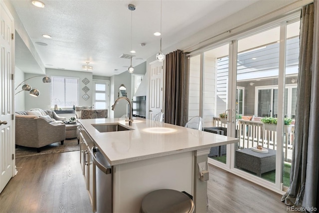 kitchen with a sink, dark wood finished floors, open floor plan, stainless steel dishwasher, and recessed lighting