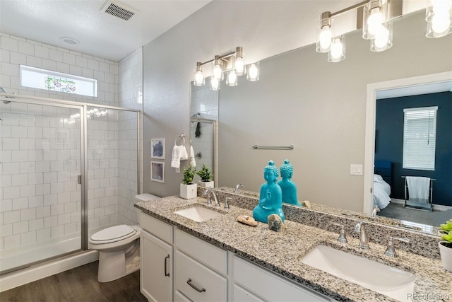 ensuite bathroom with healthy amount of natural light, toilet, a stall shower, and wood finished floors