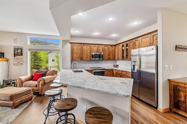 131 Creek Ln, Silverthorne, CO 80498 - kitchen with stainless steel appliances, a peninsula, light wood-style floors, a breakfast bar, and recessed lighting