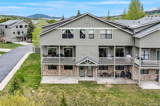 131 Creek Ln, Silverthorne, CO 80498 - back of property with board and batten siding, a mountain view, a yard, stone siding, and a patio