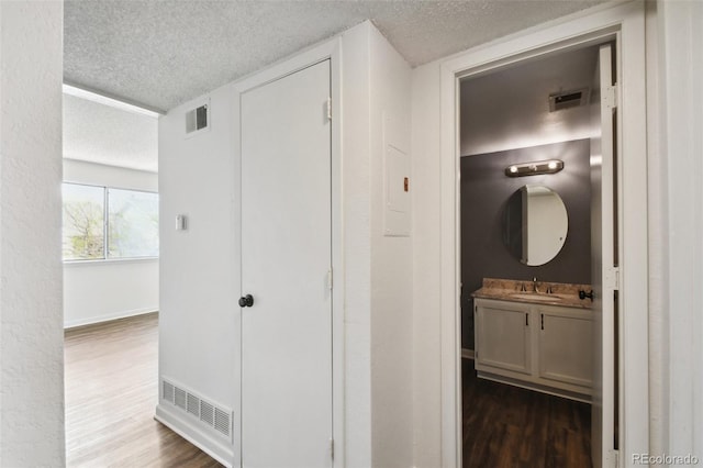 hallway featuring dark wood-type flooring, a textured ceiling, and sink