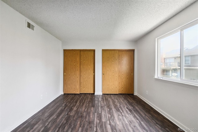 unfurnished bedroom with a textured ceiling and dark hardwood / wood-style floors