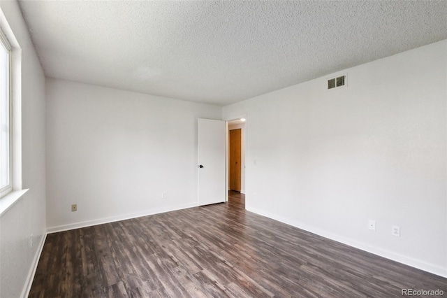 empty room with a textured ceiling and dark hardwood / wood-style flooring