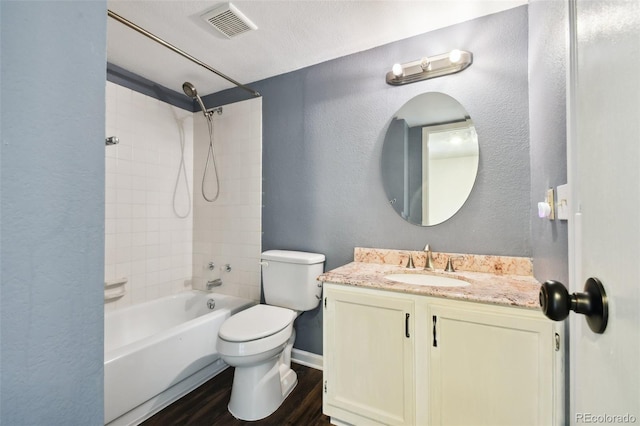 full bathroom featuring toilet, hardwood / wood-style flooring, a textured ceiling, tiled shower / bath combo, and vanity