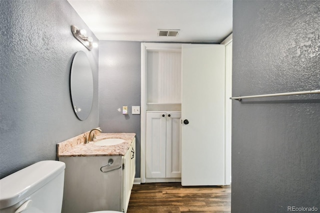 bathroom with wood-type flooring, toilet, and vanity