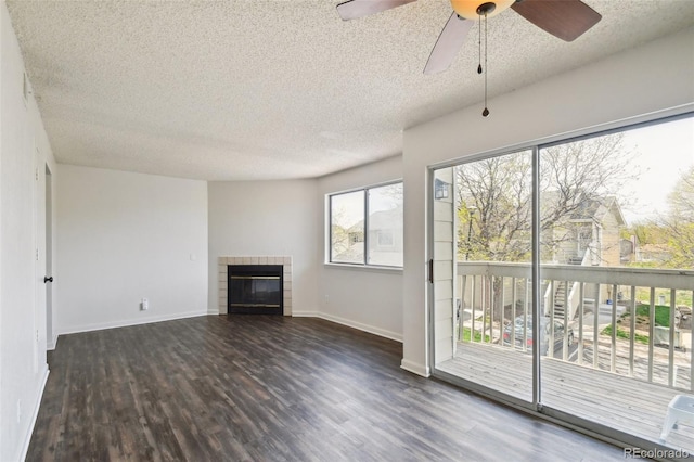 unfurnished living room with ceiling fan, a tile fireplace, a textured ceiling, and dark hardwood / wood-style flooring