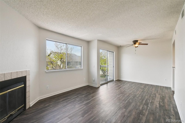 unfurnished living room with ceiling fan, a tiled fireplace, a textured ceiling, and dark hardwood / wood-style flooring