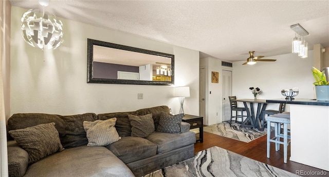 living room featuring a textured ceiling, dark wood finished floors, visible vents, and a ceiling fan